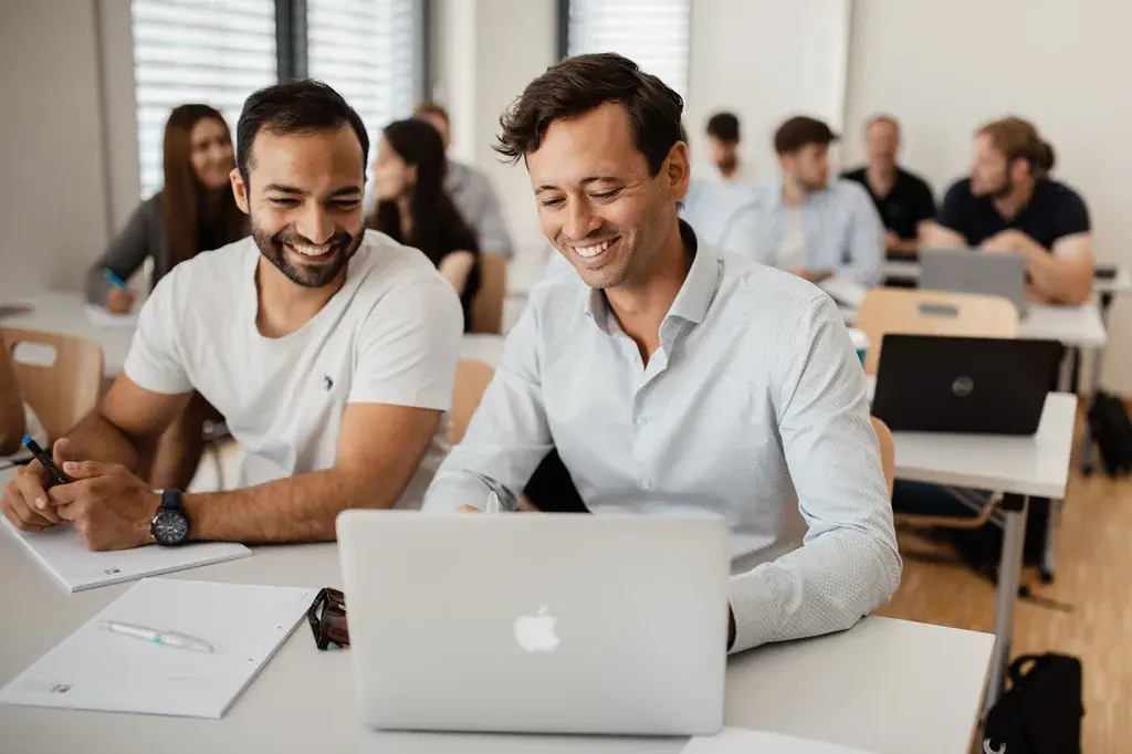 Zwei Kollegen werten gemeinsam Zahlen am Laptop aus